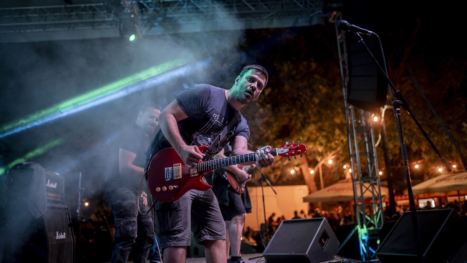 Band performing under stage lights at an outdoor evening event